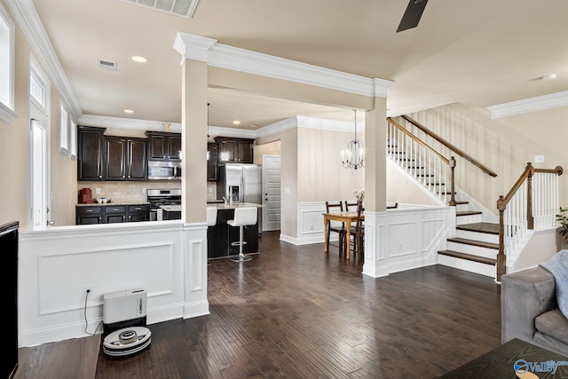 kitchen featuring a breakfast bar, stainless steel appliances, dark brown cabinetry, ornamental molding, and dark hardwood / wood-style flooring