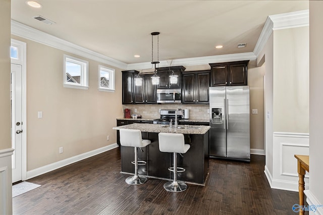 kitchen featuring pendant lighting, sink, a breakfast bar, appliances with stainless steel finishes, and an island with sink