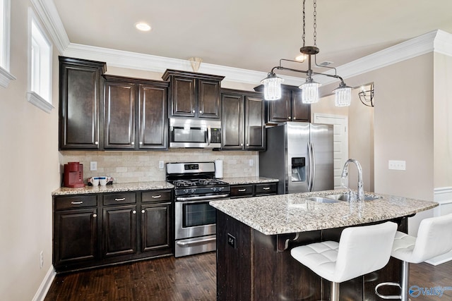 kitchen with appliances with stainless steel finishes, sink, hanging light fixtures, dark brown cabinets, and a center island with sink