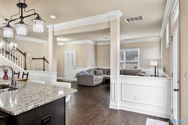 kitchen with ornamental molding, dark hardwood / wood-style floors, a center island with sink, and dark brown cabinetry