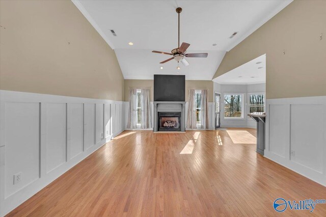 unfurnished living room with a fireplace with flush hearth, a decorative wall, visible vents, ceiling fan, and light wood-type flooring