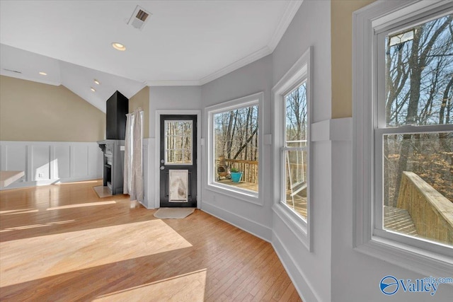 entrance foyer featuring visible vents, a fireplace, ornamental molding, lofted ceiling, and light wood-style floors
