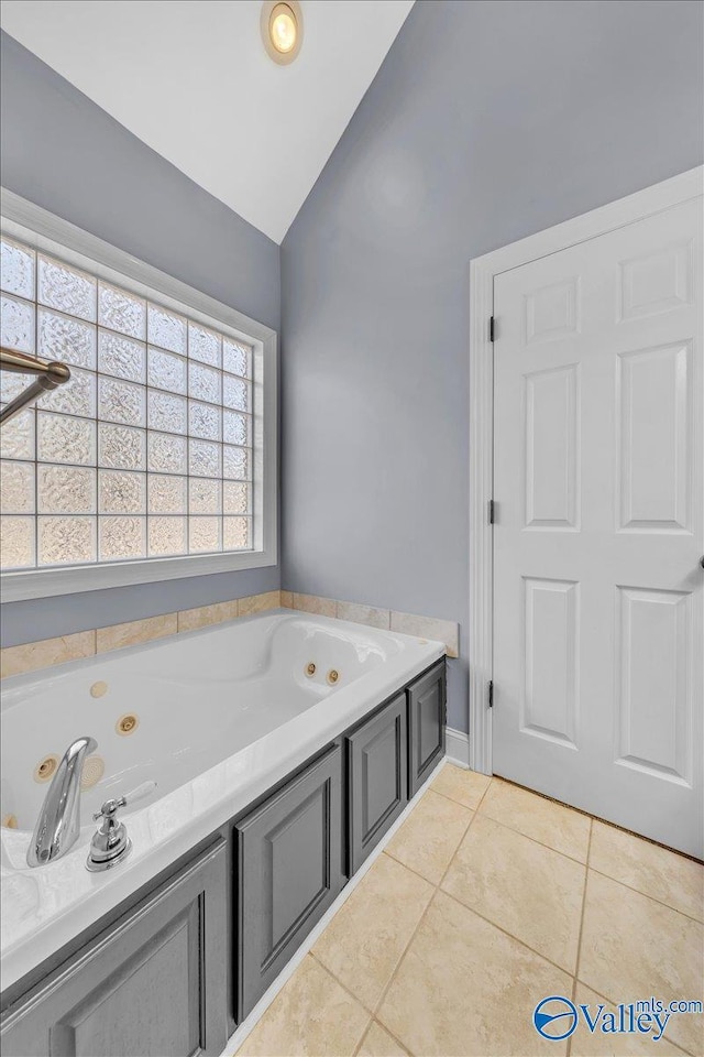 bathroom featuring tile patterned floors, a whirlpool tub, and lofted ceiling