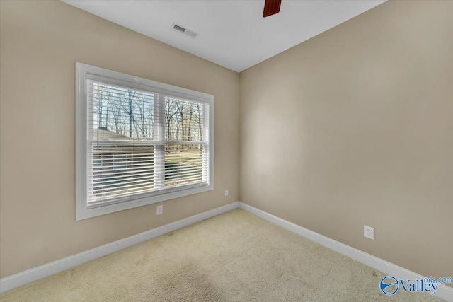carpeted spare room with baseboards, ceiling fan, and visible vents