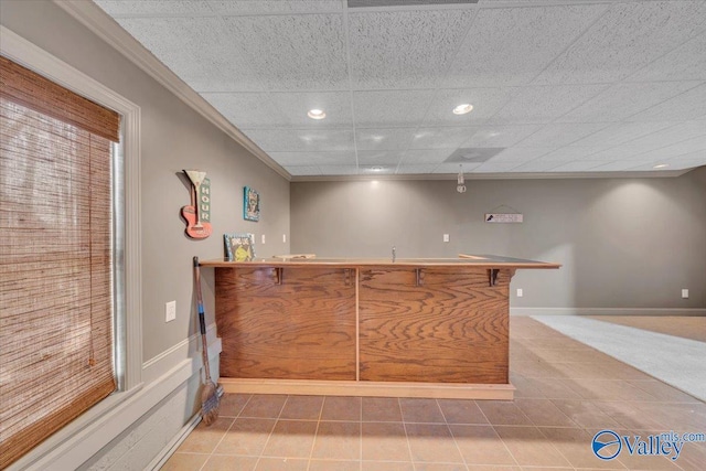 bar featuring tile patterned floors, crown molding, indoor bar, baseboards, and recessed lighting