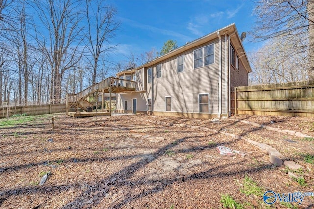 rear view of property with fence, a wooden deck, and stairway