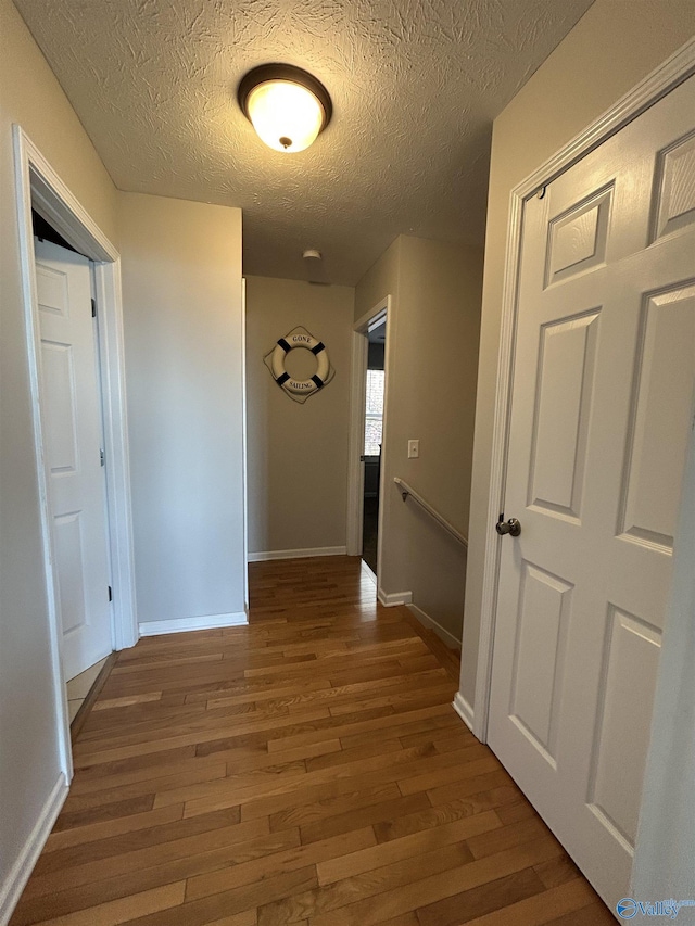 hall with dark hardwood / wood-style floors and a textured ceiling