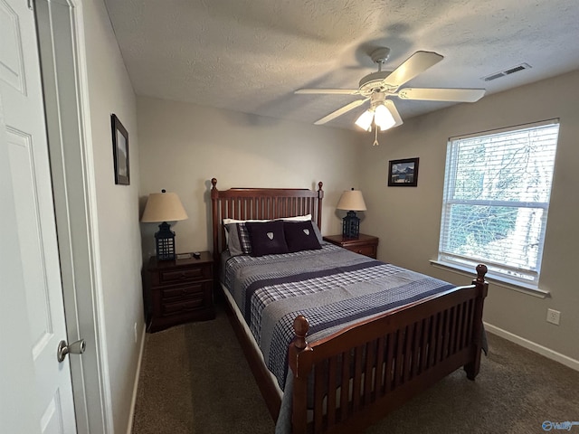 bedroom featuring ceiling fan, dark carpet, and a textured ceiling