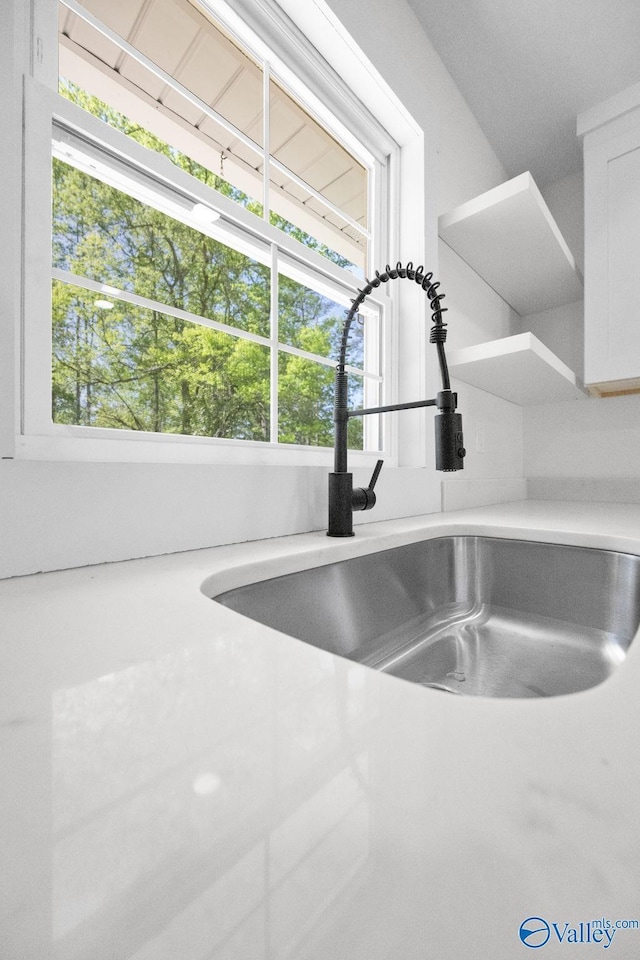 room details featuring white cabinets, open shelves, a sink, and light countertops