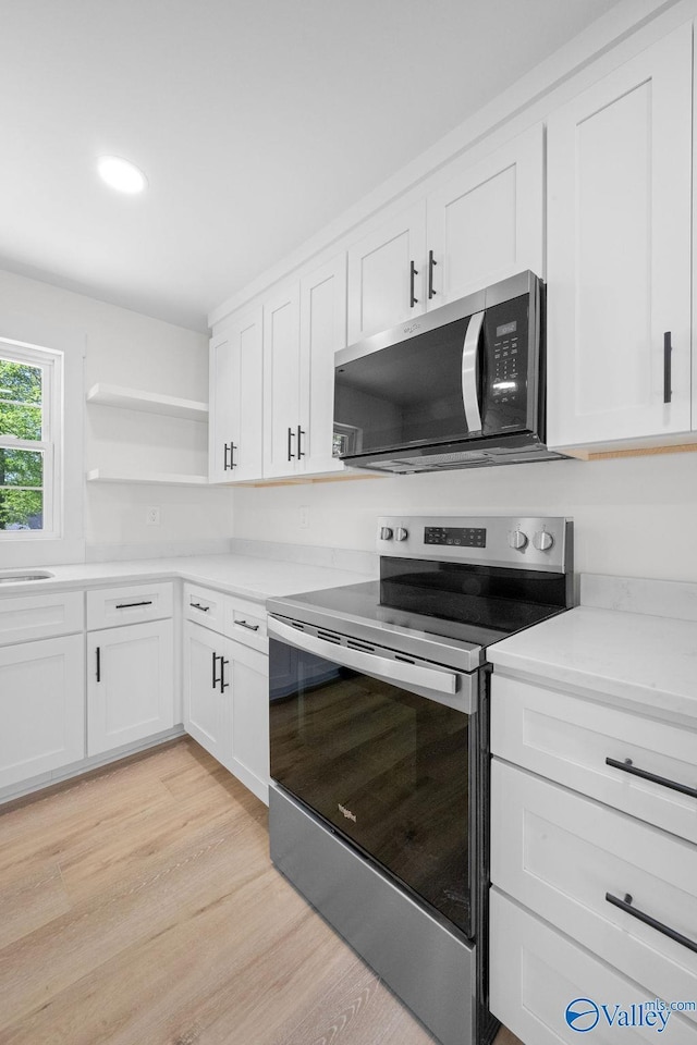 kitchen featuring open shelves, white cabinetry, and stainless steel appliances