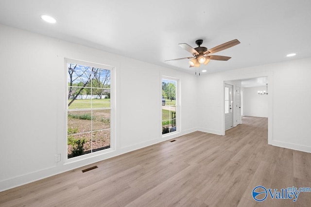 unfurnished living room with light wood finished floors, baseboards, recessed lighting, visible vents, and ceiling fan with notable chandelier