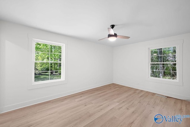 unfurnished room with a wealth of natural light, a ceiling fan, visible vents, and light wood finished floors