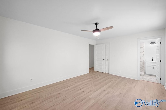 unfurnished bedroom featuring light wood finished floors, ensuite bath, baseboards, and a ceiling fan