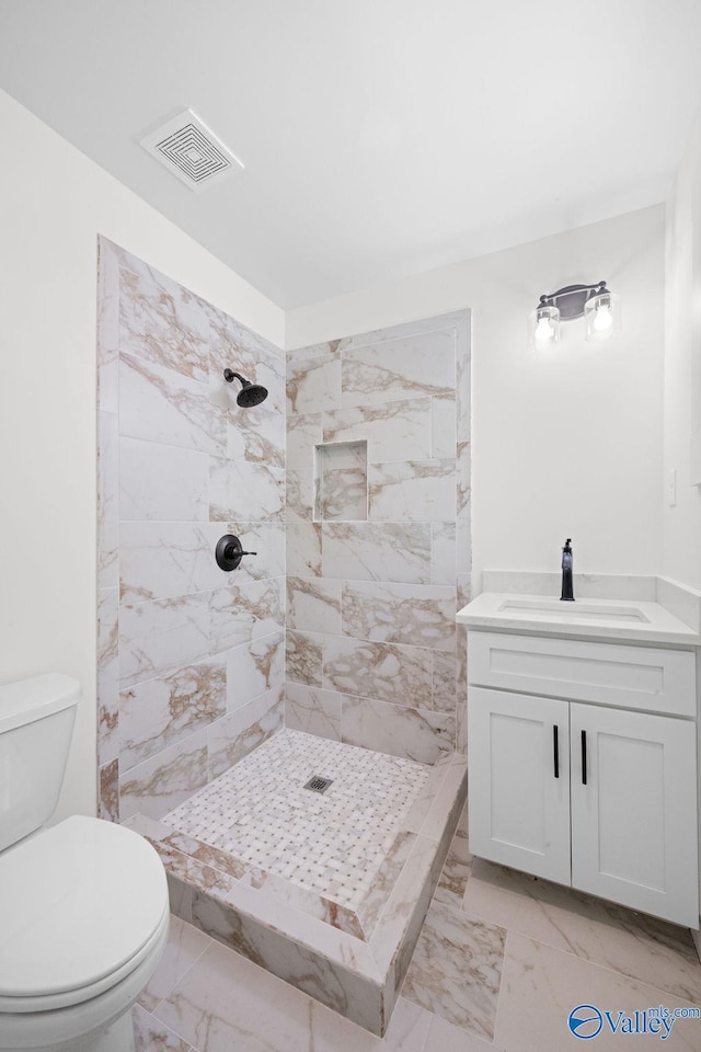 full bath featuring tiled shower, visible vents, marble finish floor, and toilet