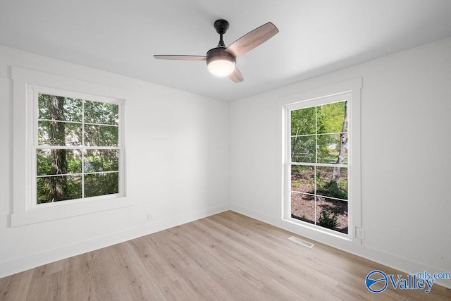 spare room with light wood-style floors, visible vents, a ceiling fan, and baseboards