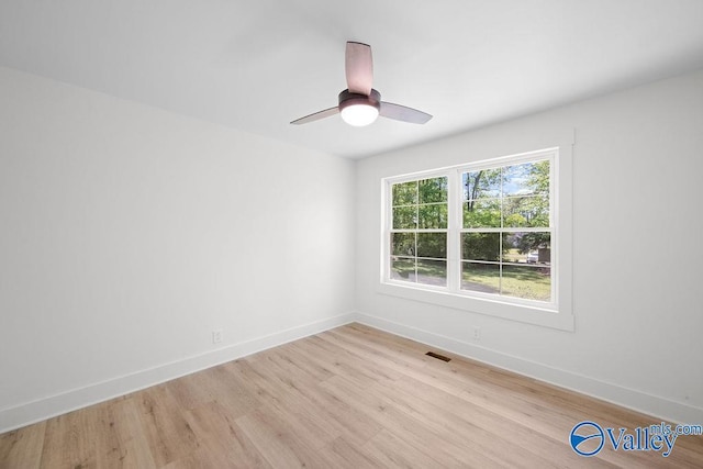 empty room featuring light wood-type flooring, baseboards, and visible vents