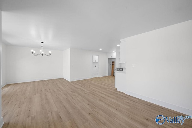 unfurnished living room featuring light wood-type flooring, baseboards, recessed lighting, and a notable chandelier