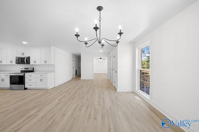 kitchen featuring light wood finished floors, stainless steel appliances, white cabinets, baseboards, and a notable chandelier