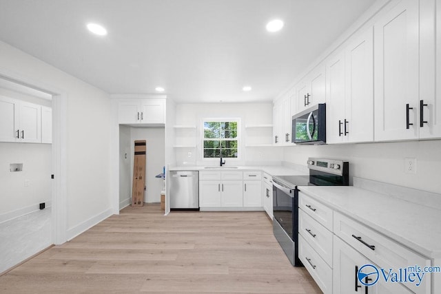 kitchen featuring open shelves, a sink, light wood-style floors, white cabinetry, and appliances with stainless steel finishes