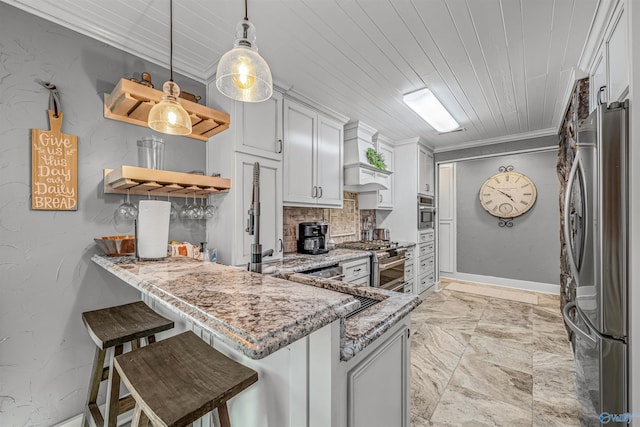 kitchen with appliances with stainless steel finishes, kitchen peninsula, decorative light fixtures, and a breakfast bar area