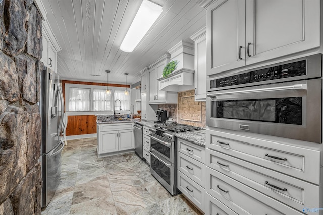 kitchen with decorative backsplash, hanging light fixtures, stainless steel appliances, kitchen peninsula, and sink