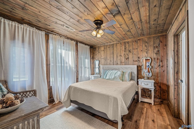 bedroom with wood ceiling, wooden walls, light wood-type flooring, and ceiling fan