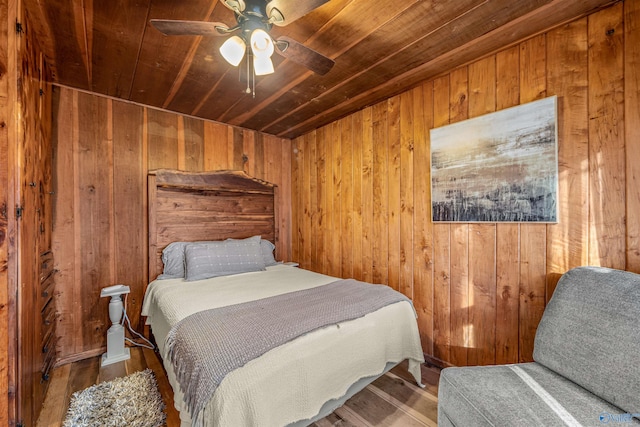 bedroom featuring ceiling fan, hardwood / wood-style flooring, wooden ceiling, and wooden walls