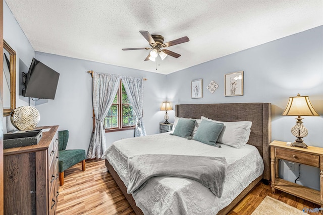 bedroom with ceiling fan, a textured ceiling, and light hardwood / wood-style floors