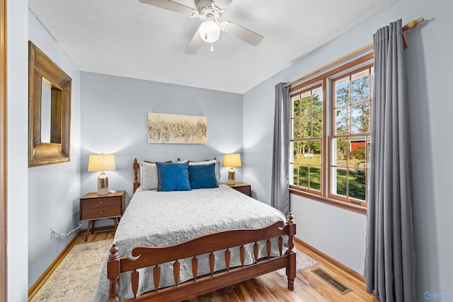 bedroom with hardwood / wood-style floors, a textured ceiling, and ceiling fan