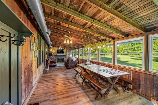 sunroom / solarium featuring wood ceiling, lofted ceiling with beams, a fireplace, and ceiling fan