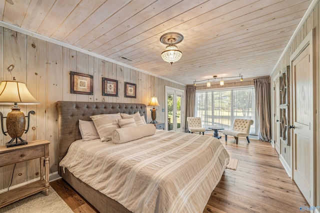 bedroom with wood ceiling, rail lighting, light wood-type flooring, ornamental molding, and wood walls