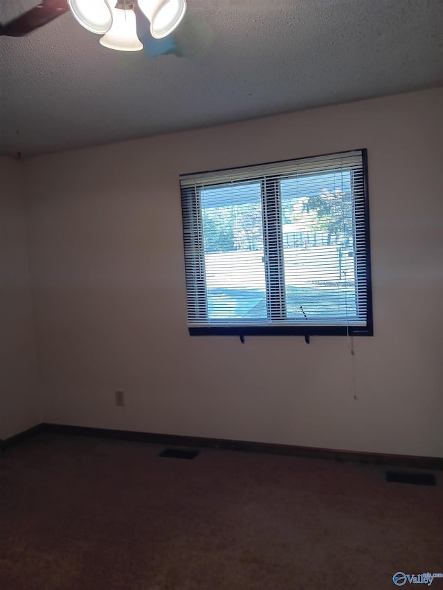 carpeted empty room featuring a textured ceiling