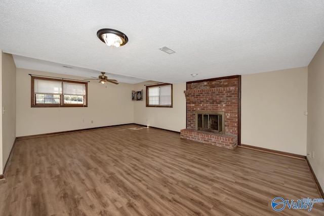 unfurnished living room with a textured ceiling, dark hardwood / wood-style flooring, and a brick fireplace