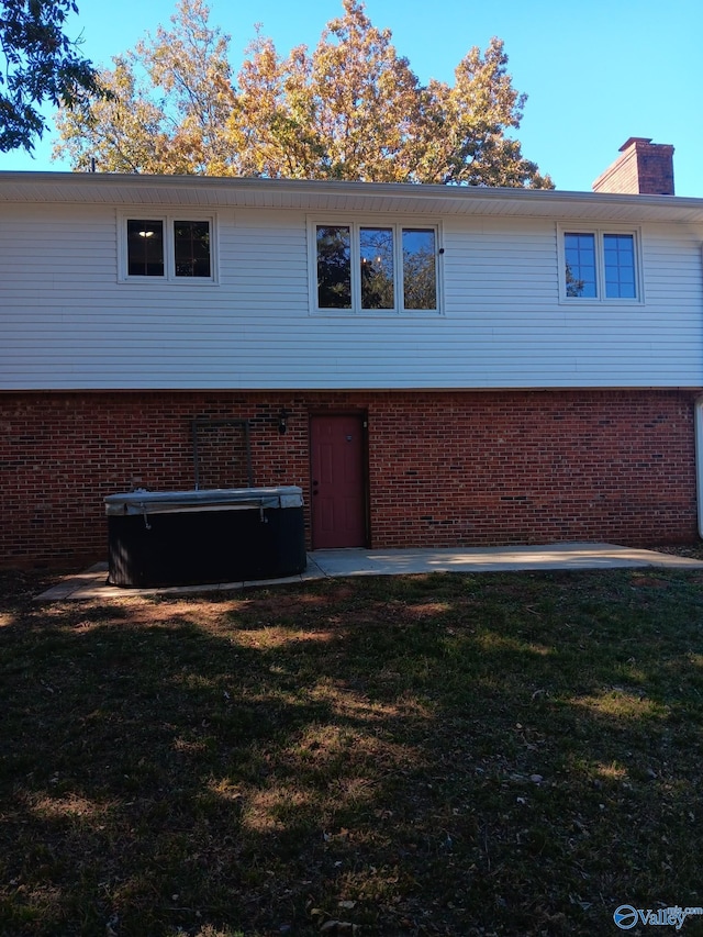 view of home's exterior featuring a lawn and a hot tub