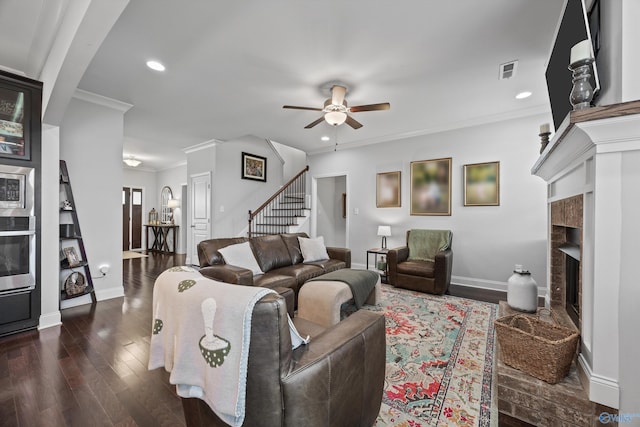 living area featuring ceiling fan, visible vents, baseboards, a fireplace with raised hearth, and dark wood-type flooring