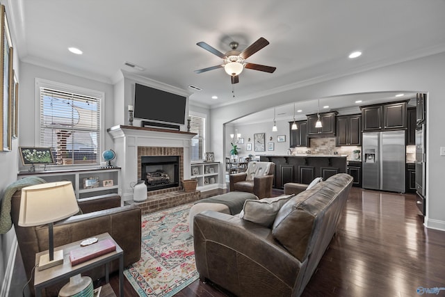 living area featuring a fireplace, a ceiling fan, recessed lighting, visible vents, and ornamental molding