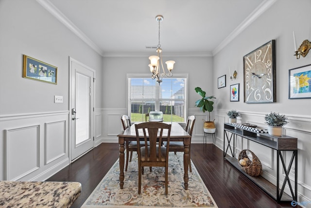 dining area with visible vents, crown molding, wainscoting, wood finished floors, and an inviting chandelier