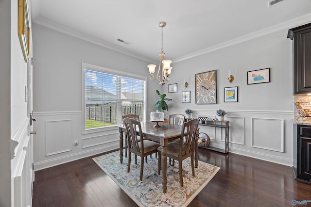 dining room with visible vents, crown molding, a wainscoted wall, a chandelier, and dark wood finished floors