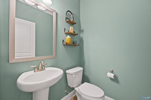 bathroom with a sink, baseboards, and toilet