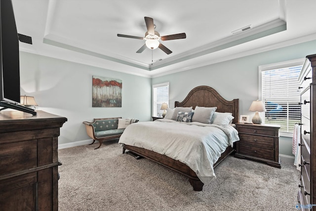 carpeted bedroom with a raised ceiling, baseboards, ornamental molding, and visible vents