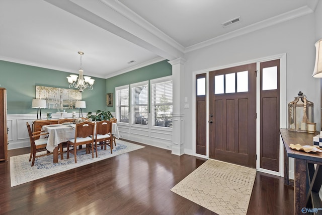 foyer with visible vents, crown molding, wainscoting, wood finished floors, and an inviting chandelier
