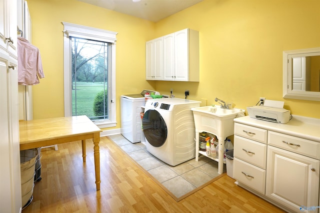 clothes washing area featuring cabinet space, independent washer and dryer, healthy amount of natural light, and light wood-style flooring