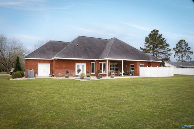 back of property with an attached garage, central air condition unit, roof with shingles, and brick siding