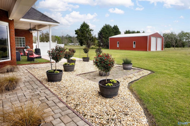 view of yard featuring ceiling fan, an outdoor structure, and a patio area