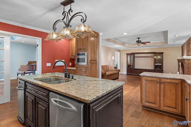 kitchen featuring light wood-style flooring, stainless steel appliances, crown molding, and a sink