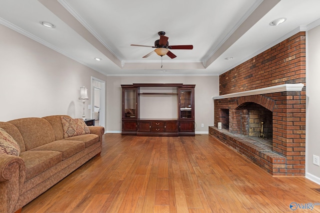 living area with hardwood / wood-style floors, a tray ceiling, crown molding, and a fireplace