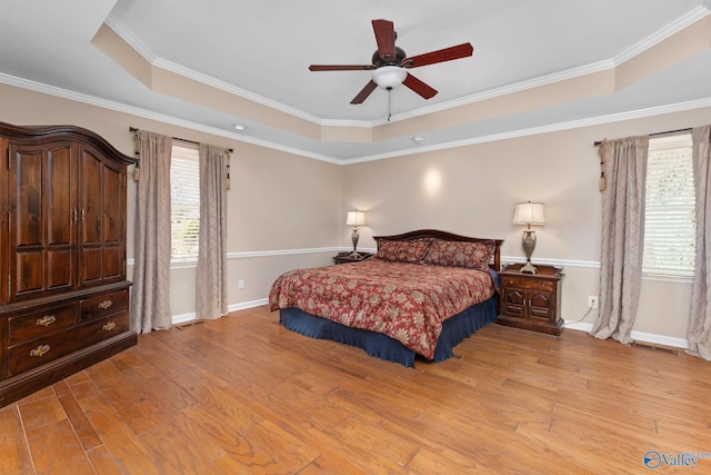 bedroom featuring a tray ceiling, baseboards, and light wood-type flooring