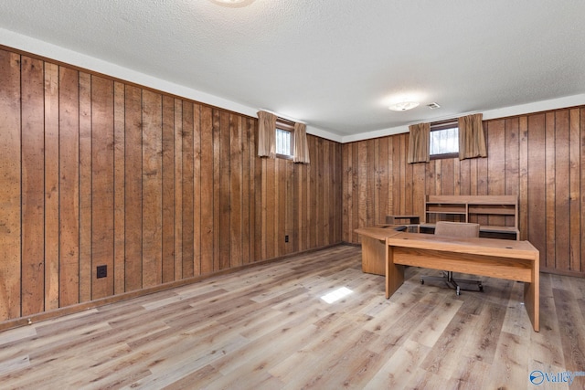 office space with a textured ceiling, wood walls, and light wood finished floors