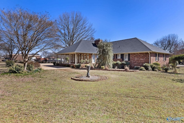 view of front of home with brick siding, a chimney, and a front lawn