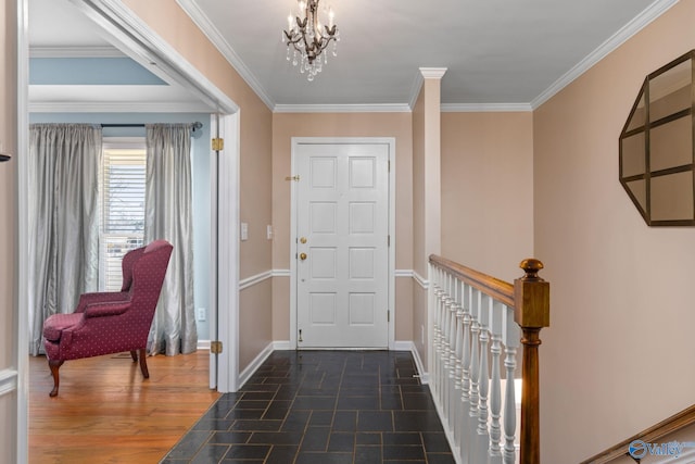 foyer entrance with dark wood-style floors, a notable chandelier, baseboards, and ornamental molding